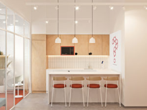 Кухню выполнили в теплых тонах, так как всё же это часть зоны отдыха. Дополнили дизайн интерьера графикой и яркими стульями.